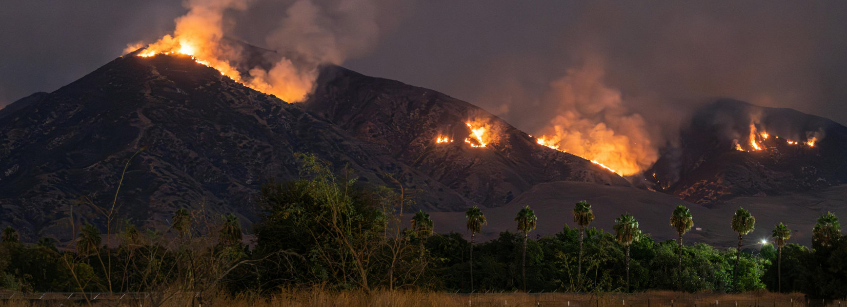 Photo of wildfires on a mountain in the distance.